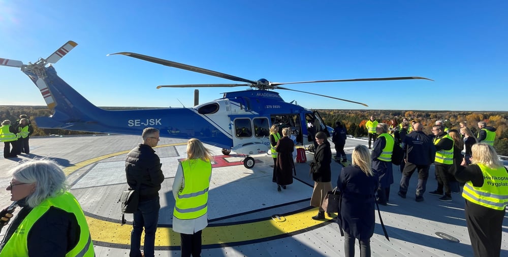 En grupp människor som står runt en helikopter.