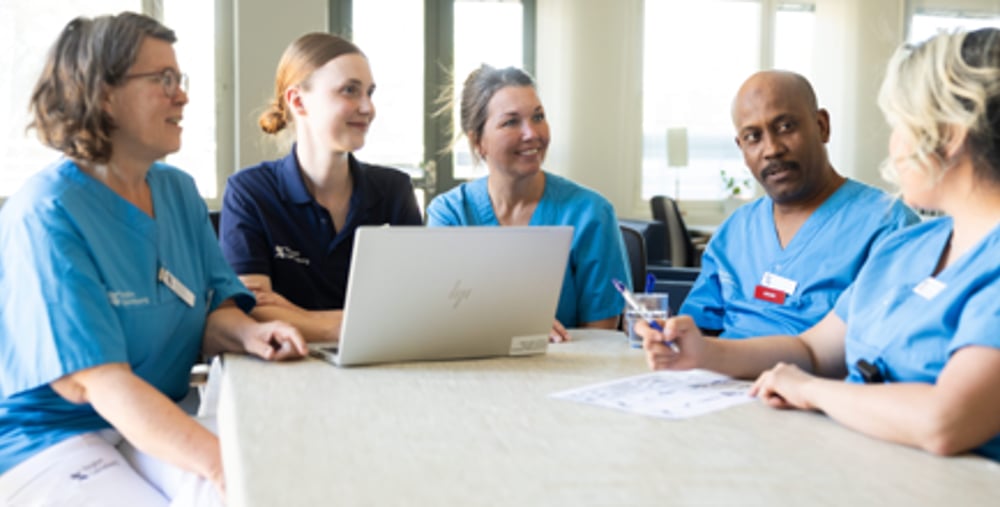 En grupp sjuksköterskor som sitter runt en bärbar dator.