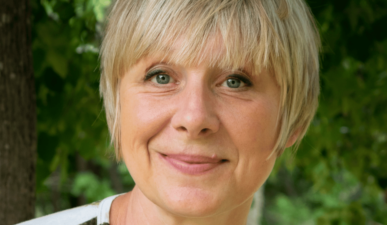 En kvinna med blont hår ler mot kameran.