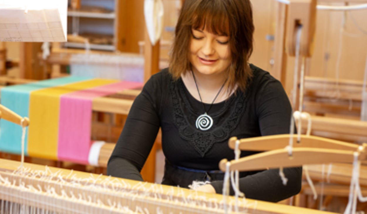 En person arbetar på en vävstol.