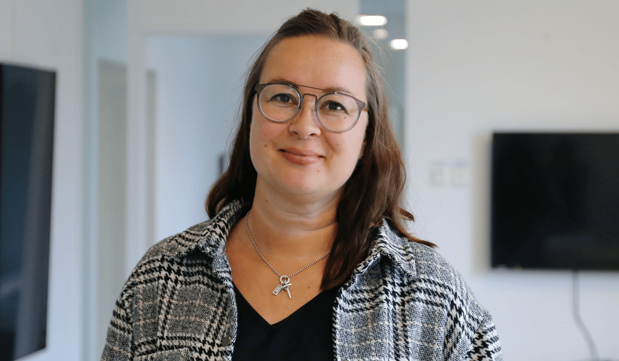 En kvinna med glasögon som står framför en platt-tv.