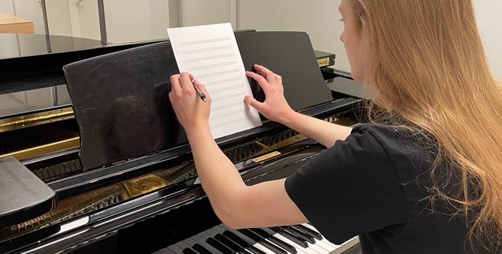 Person vid svart piano som komponerar musik