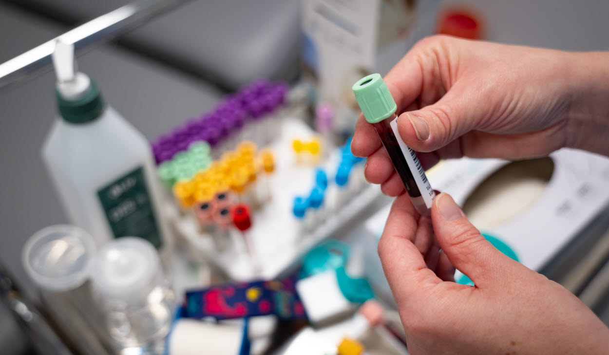 Händer som håller ett provrör med blodprov