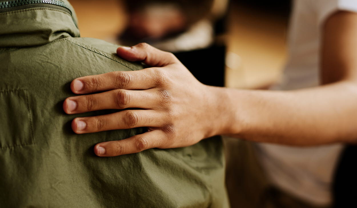 Hand of young supportive man consoling his friend or one of attendants with post traumatic syndrome caused by dramatic life event