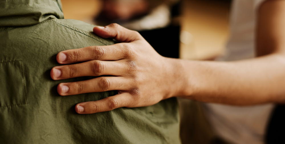 Hand of young supportive man consoling his friend or one of attendants with post traumatic syndrome caused by dramatic life event